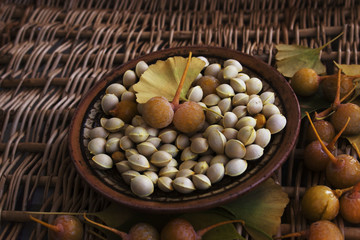 Fruits, bones and leaves of ginkgo biloba on a wicker surface. Studio.