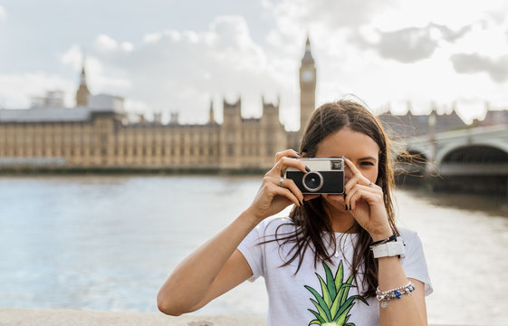 UK, London, beautiful woman taking a picture near Westminster Bridge