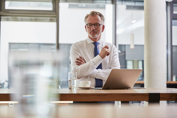 Businessman waiting at the airport, using laptop and drinking coffee