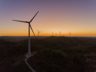 Obraz premium Aerial panoramic Wind farm turbines silhouette at sunset. Clean renewable energy power generating windmills. Algarve countryside.
