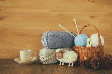 Fototapeta na wymiar warm and cozy yarn balls of wool and hot cup of coffee on wooden table.