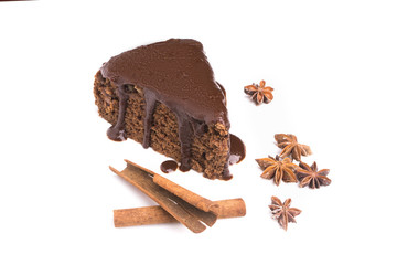 A piece of chocolate cake, cinnamon sticks and anise star isolated on white background