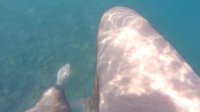 Male feet swimming underwater on sea during summer vacation. Point of view of young man. POV Close up Slow motion
