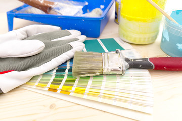 Color palette guide and painting supplies, paint brushes and color cans on wooden background