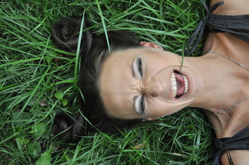 Young woman lying on grass a garden outdoor portrait. Close up portrait of young  girl woman with dark hair.View from above top overhead. Concept of spring summer youth happiness