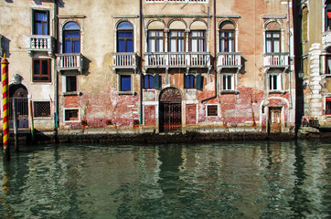 facade of a stately Venetian palace, overlooking a sunny canal and needing restoration