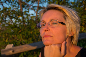 beautiful woman with glasses in nature at sunset