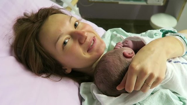 Childbirth. Mother holding her newborn baby child after labor in a hospital. Mother giving birth to a baby boy. Parent and infant first moments of bonding.