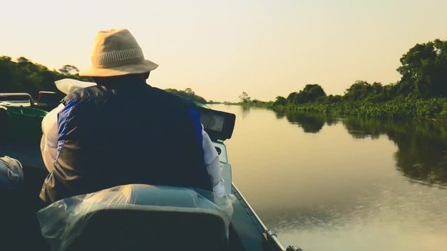 Fisherman navigating in his boat making a curve on the river in Pantanal - Brazil. 