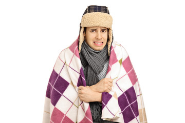 Young man covered with a blanket feeling cold