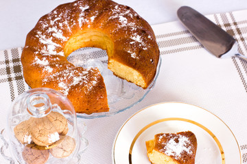 Cupcake with powdered sugar in a vase. A slice of cake on a white dish. Almond cookies in a glass vase.