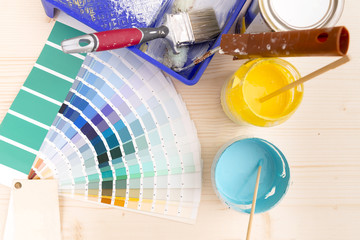 Color palette guide and painting supplies, paint brushes and color cans on wooden background