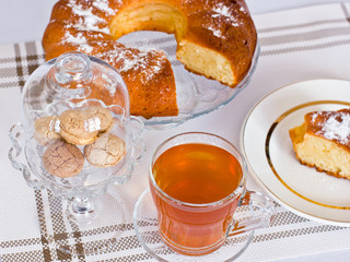 Cupcake with powdered sugar in a vase. A slice of cake on a white dish. Almond cookies in a glass vase. Herbal tea.