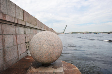 granite ball on the waterfront of the river Neva and the open foundry bridge in St. Petersburg, Russia