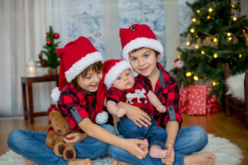 Christmas portrait of three brothers with Santa hats sitting on the floor