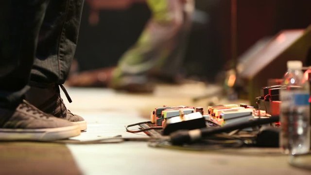 Band Low Angle Foot Pedal Board and Band Mates Playing Legs. a shot of the lower half of the stage with the legs of a band playing on stage
