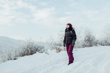 Fototapeta na wymiar Smiling woman dressed warm enjoying a walk in snowy country