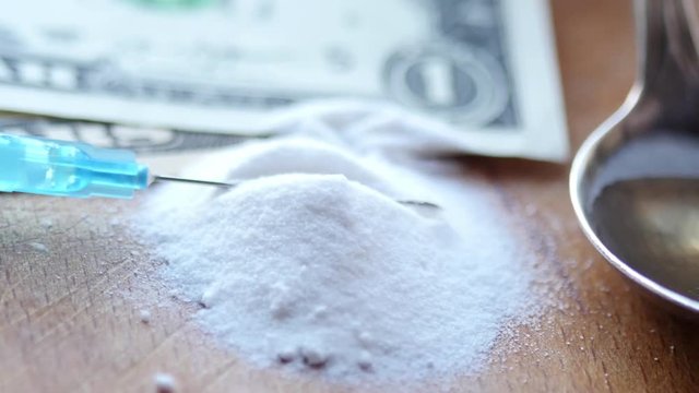 Money, drug, spoon and syringe with heroine on a table. 4K UltraHD video footage