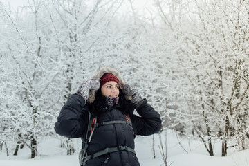 Fototapeta na wymiar Smiling woman dressed warm walking through forest in winter