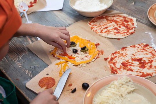 Halloween party ideas for kids ghost pizza with cheese and olives. Baby hands decorate festive pizza
