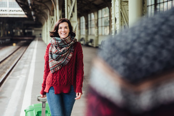 Happy woman with suitcase meets her husband, comes from abroad, has unforgettable meeting. Couple...