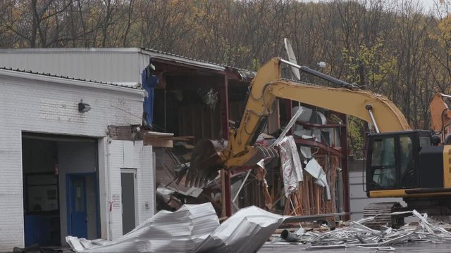Demolition of a Building with Excavator. an excavator is used to destroy a building facade
