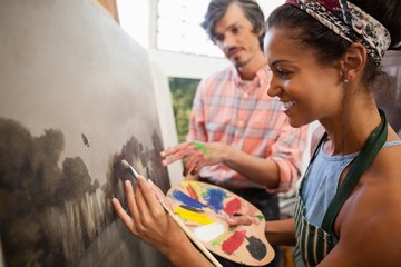 Man assisting woman in painting