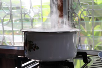 White Pot cooking boiling with steam on fire in Thai kitchen