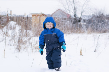 Fototapeta na wymiar Happy boy walking in a snow - winter leisure for children