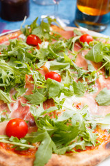 Italian pizza with ham, cherry tomatoes, arugula, mozzarella buffalo cheese. food background with selective focus