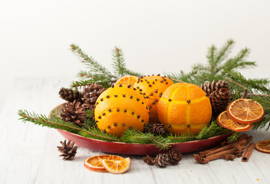 Decorated oranges with cloves on spruce branches with cones