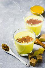 Turmeric milkshake with cinnamon on stone background. Selective focus, space for text. 