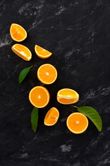 Fototapeta na wymiar still life of oranges on a black textural background on a marble top view. fruit slices on a dark background