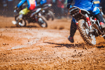 Details of flying debris during an acceleration with mountain bikes race in dirt track in sunshine day time in blurry background. Concept of focus between an accelerate in action sport