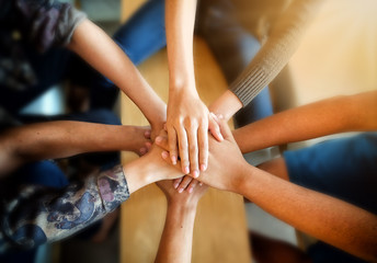 Close up top view of young people putting their hands together. Friends with stack of hands showing unity and teamwork.