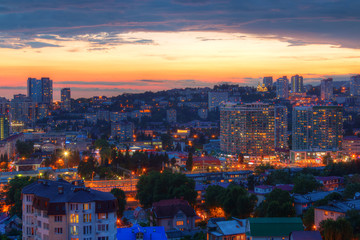 Fototapeta premium Beautiful aerial view of the illuminated city of Sochi on the background of glowing sky at twilight, Russia 
