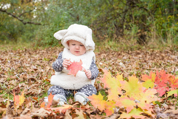 Baby dressed up as a lamb for Halloween playing in leaves