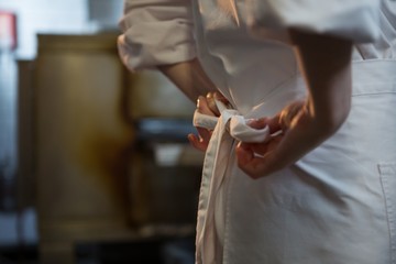 Female chef tying her uniform - obrazy, fototapety, plakaty