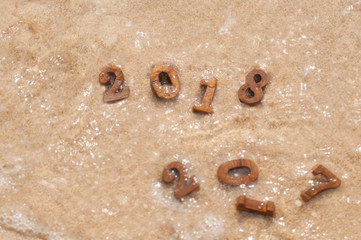 Change from 2017 to 2018 with soft wave, wood number 2018 on beach background idea
