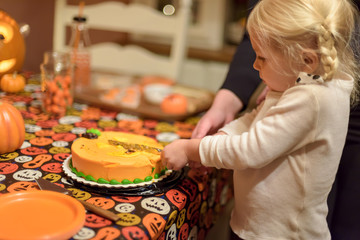 Child cutting cake at Halloween party