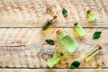 Skin care products with tea tree oil in bottles on rustic wooden background top view pattern copyspace
