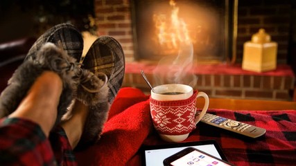 Cinemagraph of steaming hot coffee by fire in living room at Christmas feet rest on sofa