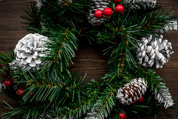 Christmas wreath woven of spruce branches with red berries on wooden background top view