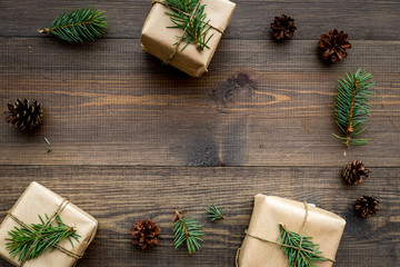 Gifts for new year wrapped in craft paper near spruce branches and cones on wooden background top view pattern copyspace