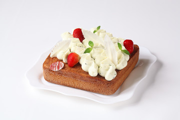 Slice of Basil Sponge Cake with Whipped Cream Cheese Frosting and Strawberries, on white plate, on white background.