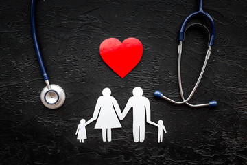 Take out health insurance for family. Stethoscope, paper heart and silhouette of family on black background top view