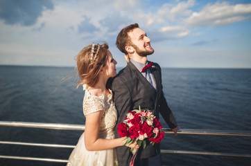 Married wedding couple standing on a wharf over the sea
