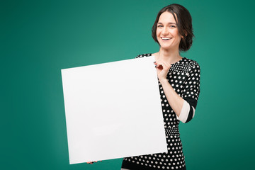 Image of beautiful woman in speckled clothes standing with paper in hands