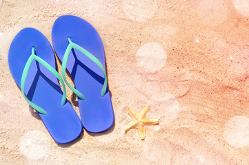 Blue flip flops on sand with starfish
