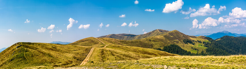 Fototapeta na wymiar footpath through rolling hills of mountain ridge. gorgeous panorama of early autumn landscape with fine weather and blue sky with some clouds. hiking direction concept